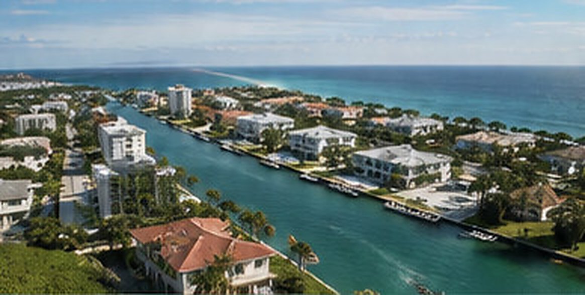 Aerial view of a waterfront residential community along a narrow waterway, with the ocean behind it