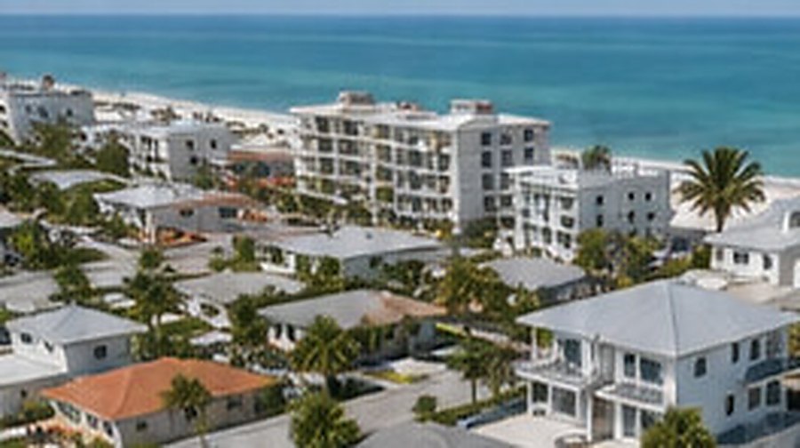 Aerial view of a coastal residential block of low-rise buildings with the beach and open water beyond