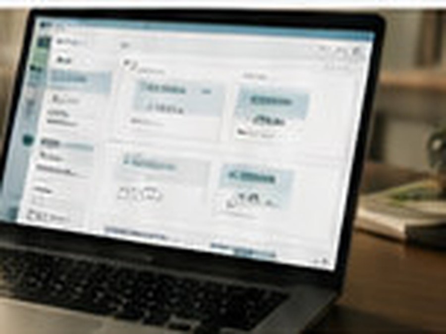 Laptop on a desk displaying a software interface with a sidebar and card panels